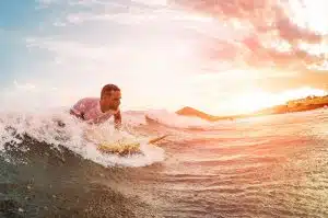 Surfer der gerade aufs Board steigt.