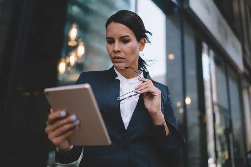 Anwältin vor modernem Glaseingang mit Tablet